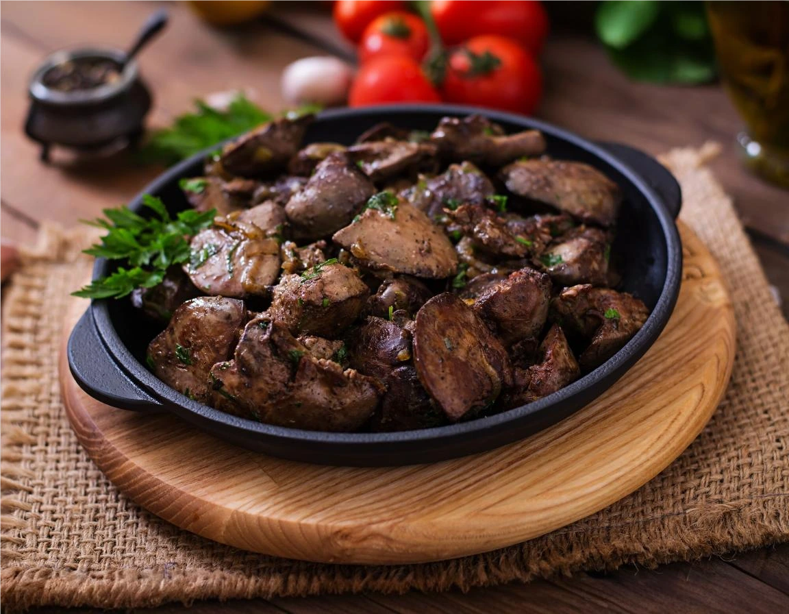 Cooked chicken hearts served on a plate garnished with fresh herbs.